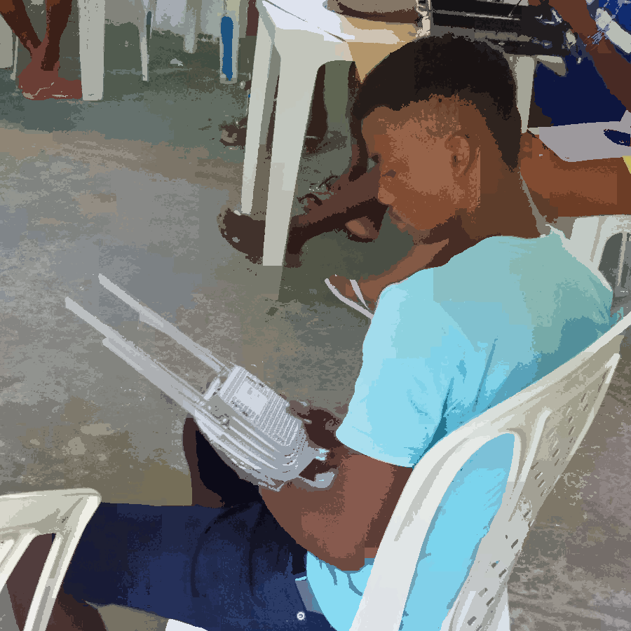 Na imagem podemos ver um jovem, sentado em uma cadeira, segurando um roteador em suas mãos.